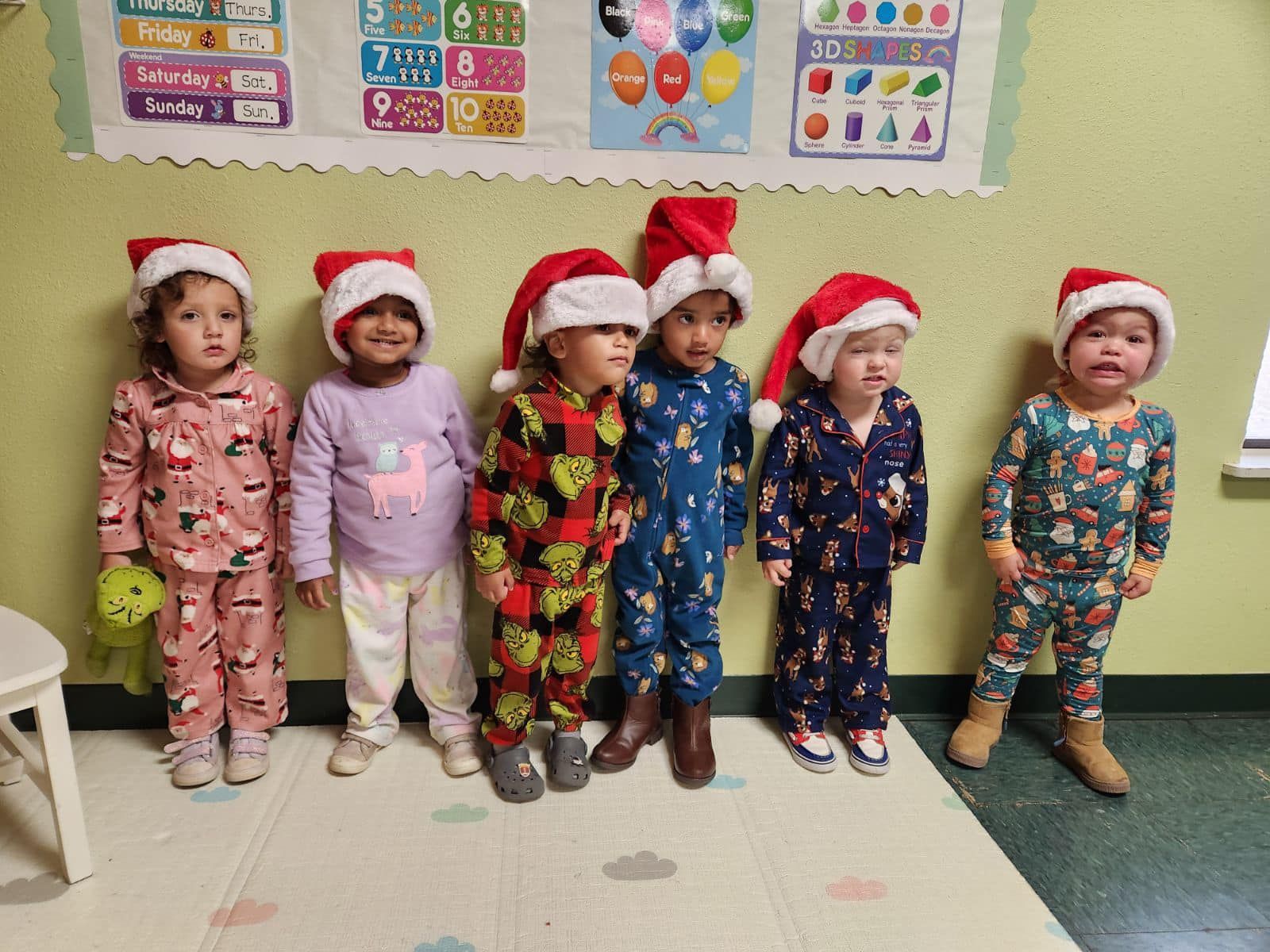 a group of children wearing santa hats and pajamas are standing next to each other .