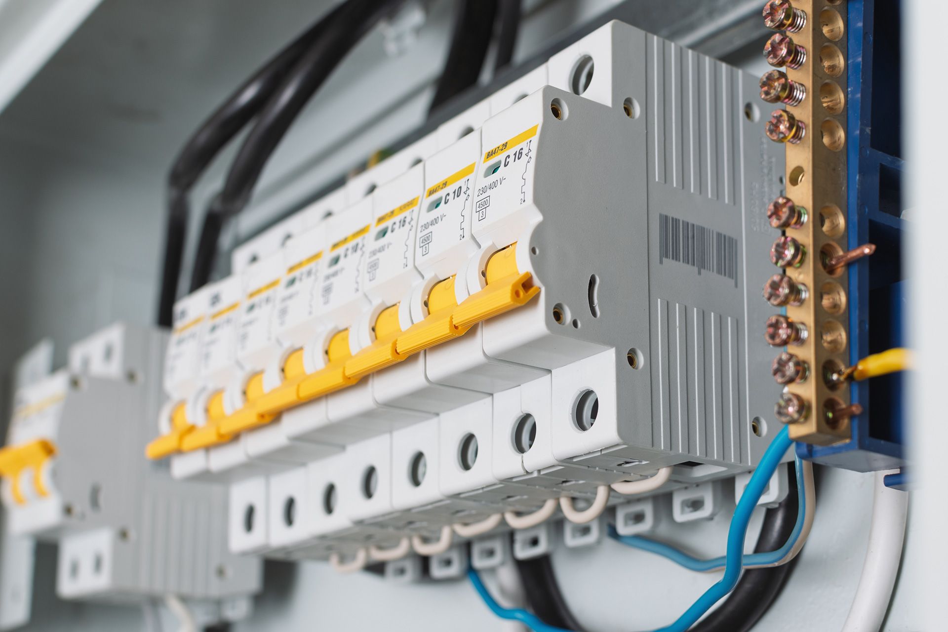 Circuit breaker box with rows of switches and copper bus bar.