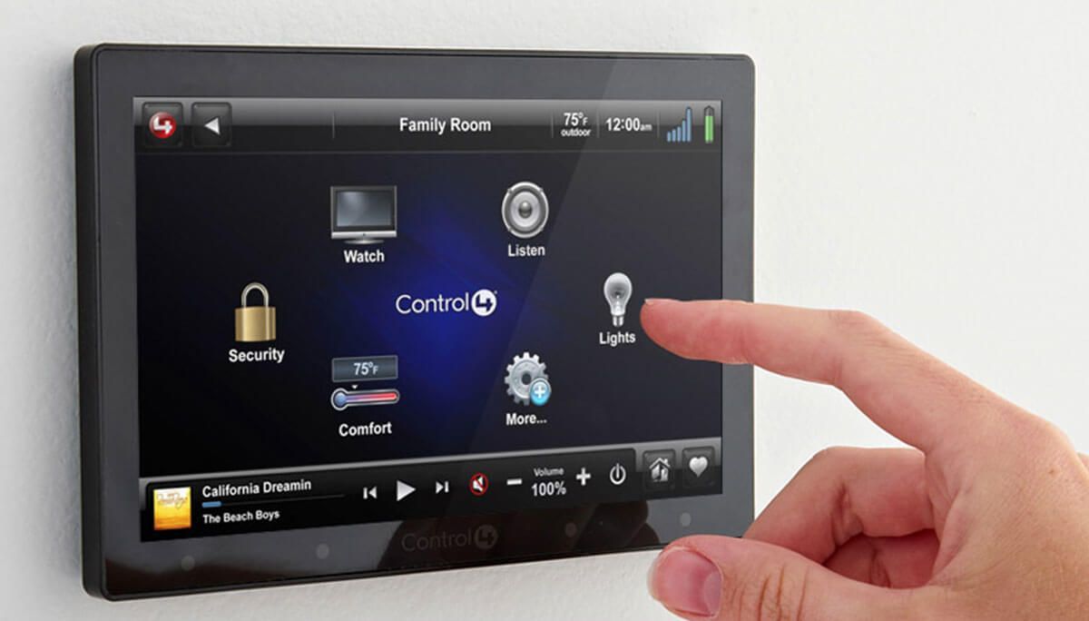 Silver intercom panel with a keypad and screen on a dark gray wall, near glass.