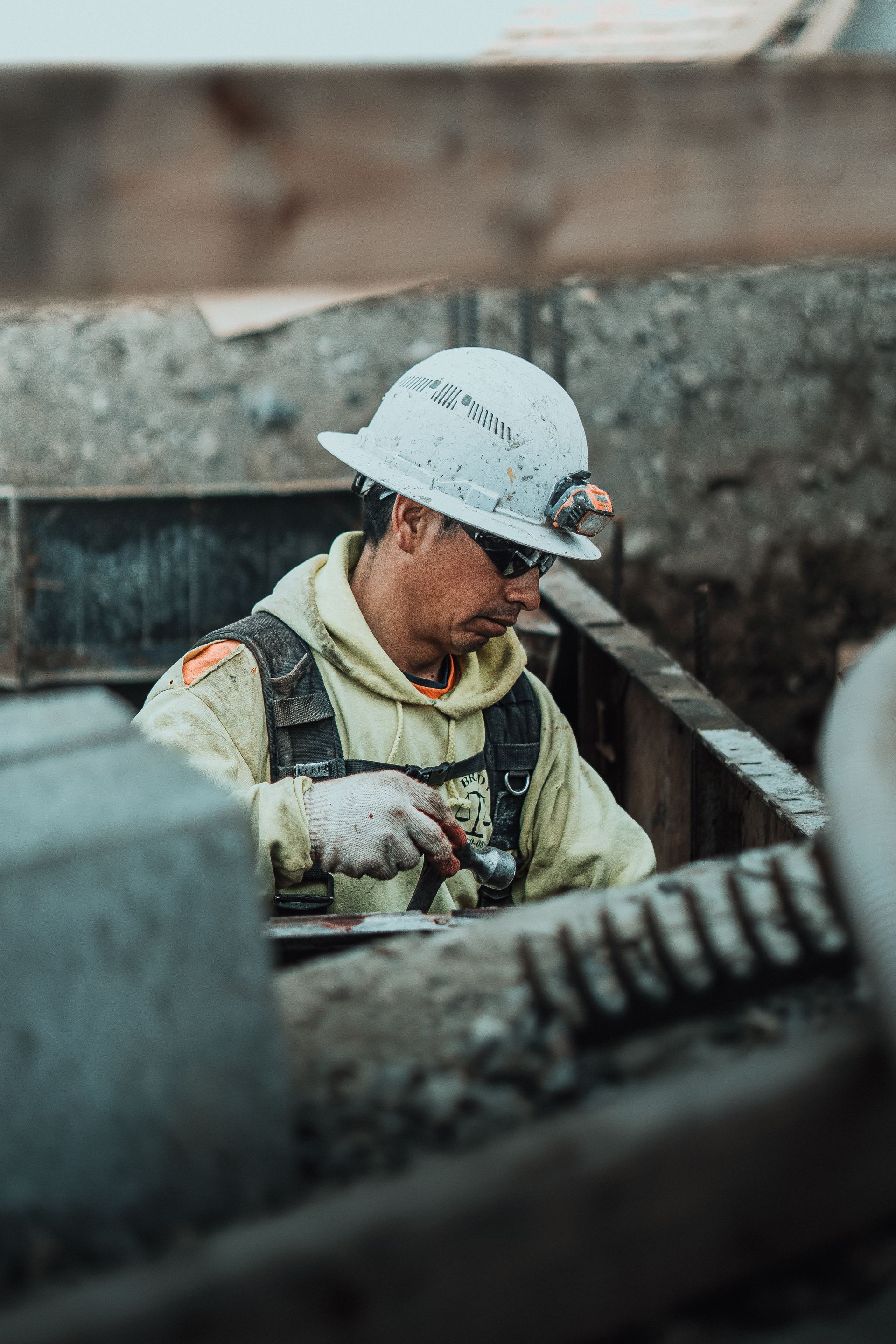 Construction worker wearing a hard hat and safety vest, working on a concrete structure.
