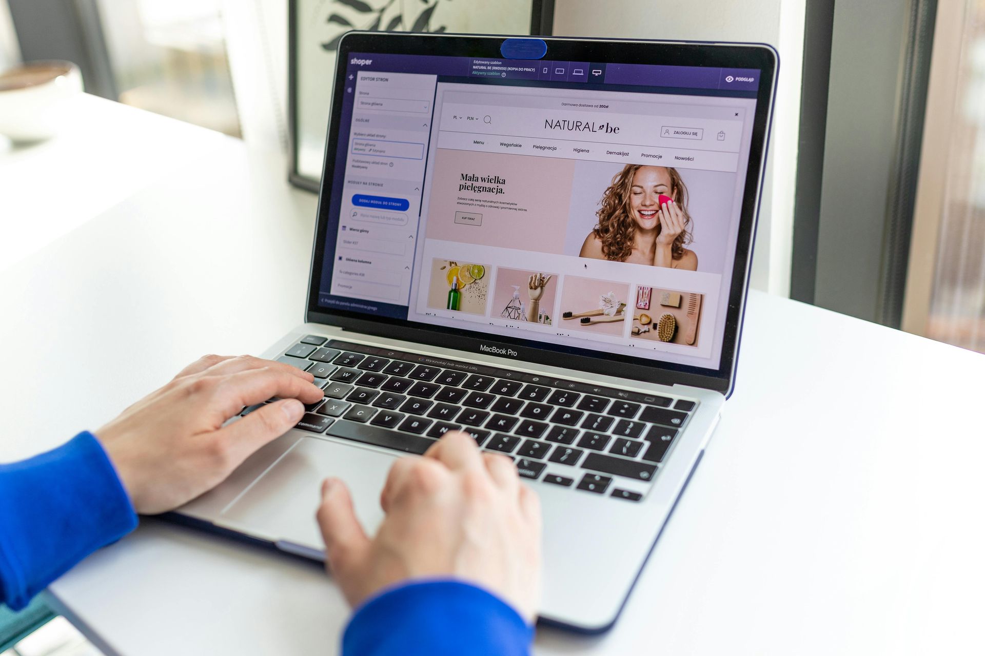 Hands typing on a laptop displaying a website with product images.