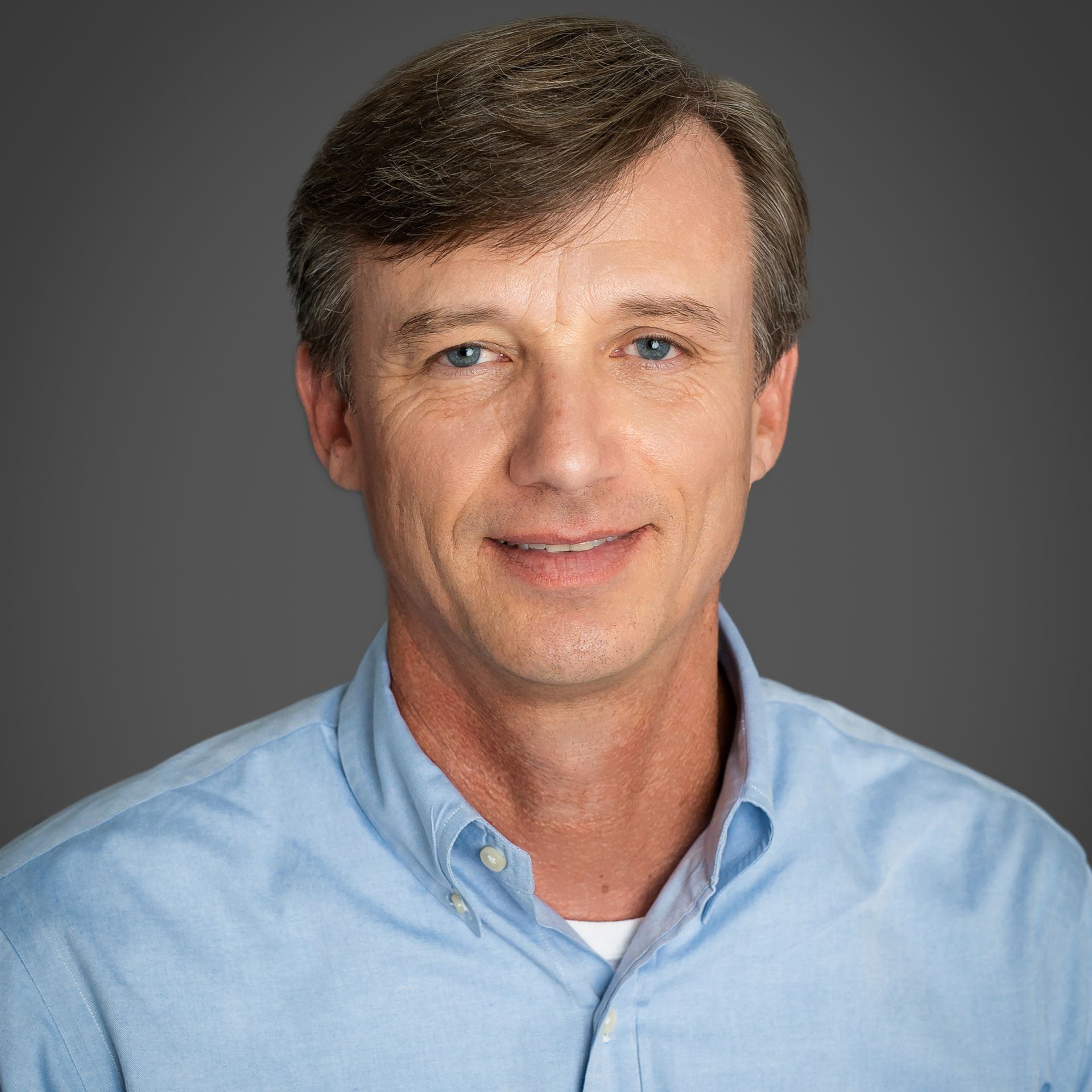 A man in a blue shirt is smiling for the camera.
