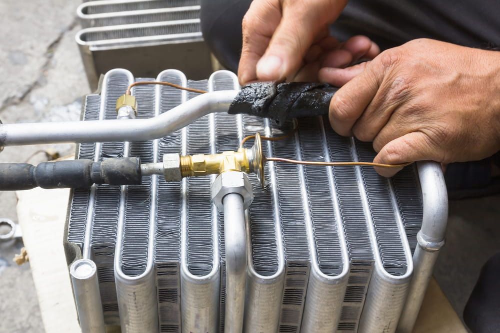 A Man Is Working On A Radiator With A Wrench — Bear Air Conditioning In Toukley, NSW