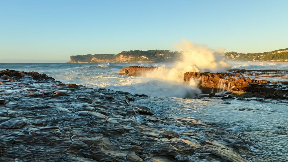 The Waves Are Crashing Against The Rocks On The Beach — Bear Air Conditioning In Central Coast, NSW
