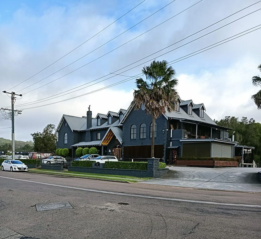 A Large House With A Lot Of Cars Parked In Front Of It — Bear Air Conditioning In Erina, NSW