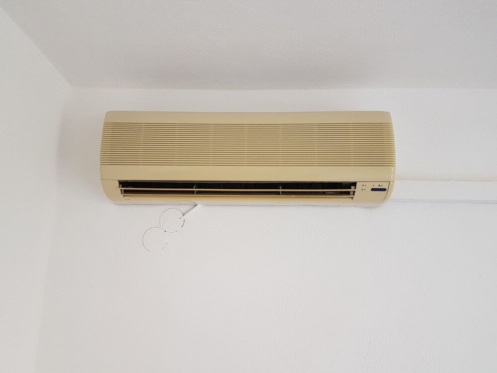 A Wall Mounted Air Conditioner Is Hanging On A White Wall — Bear Air Conditioning In Toukley, NSW
