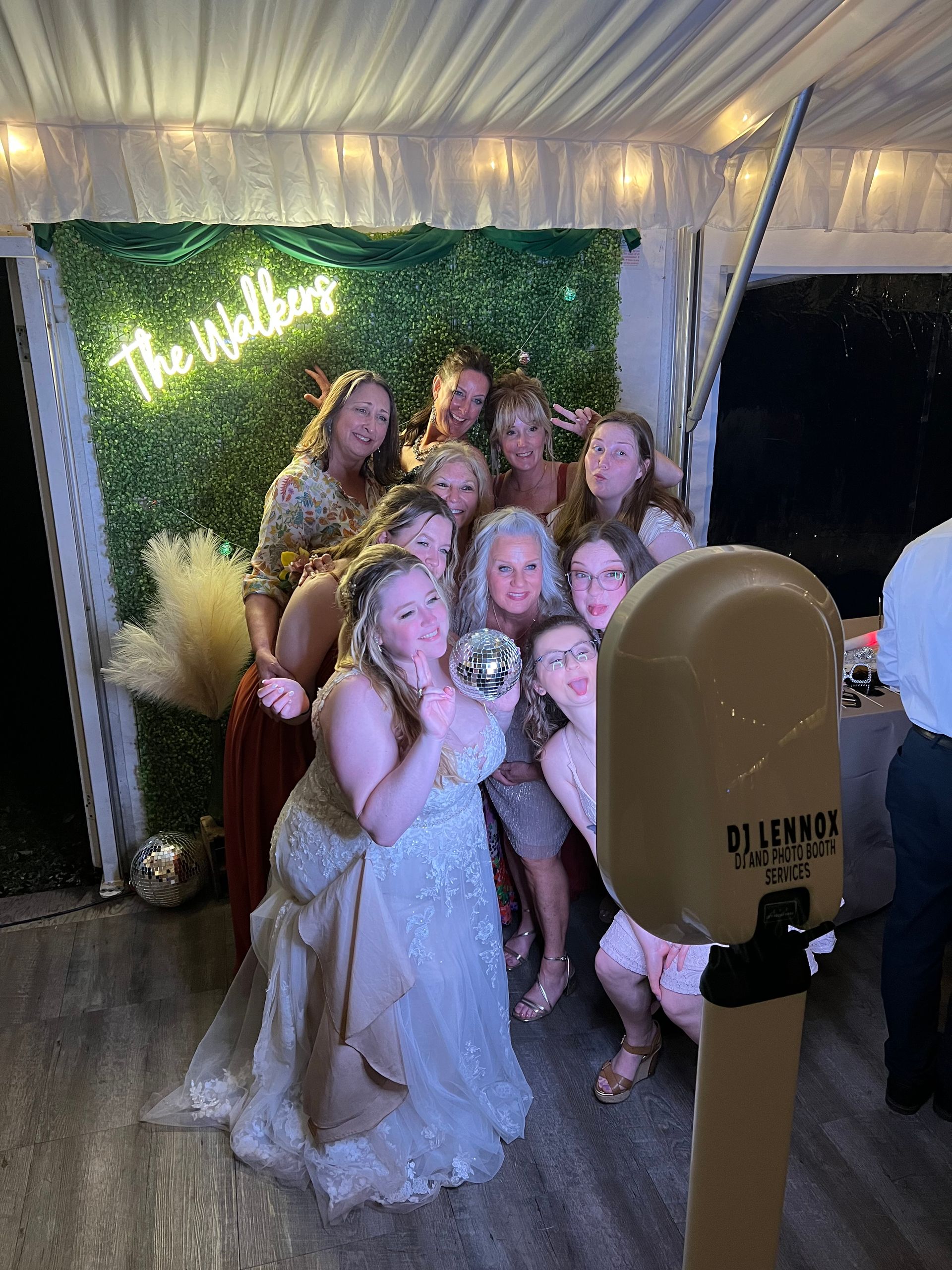 Group of people posing for a photo booth picture at an event with a green wall backdrop.