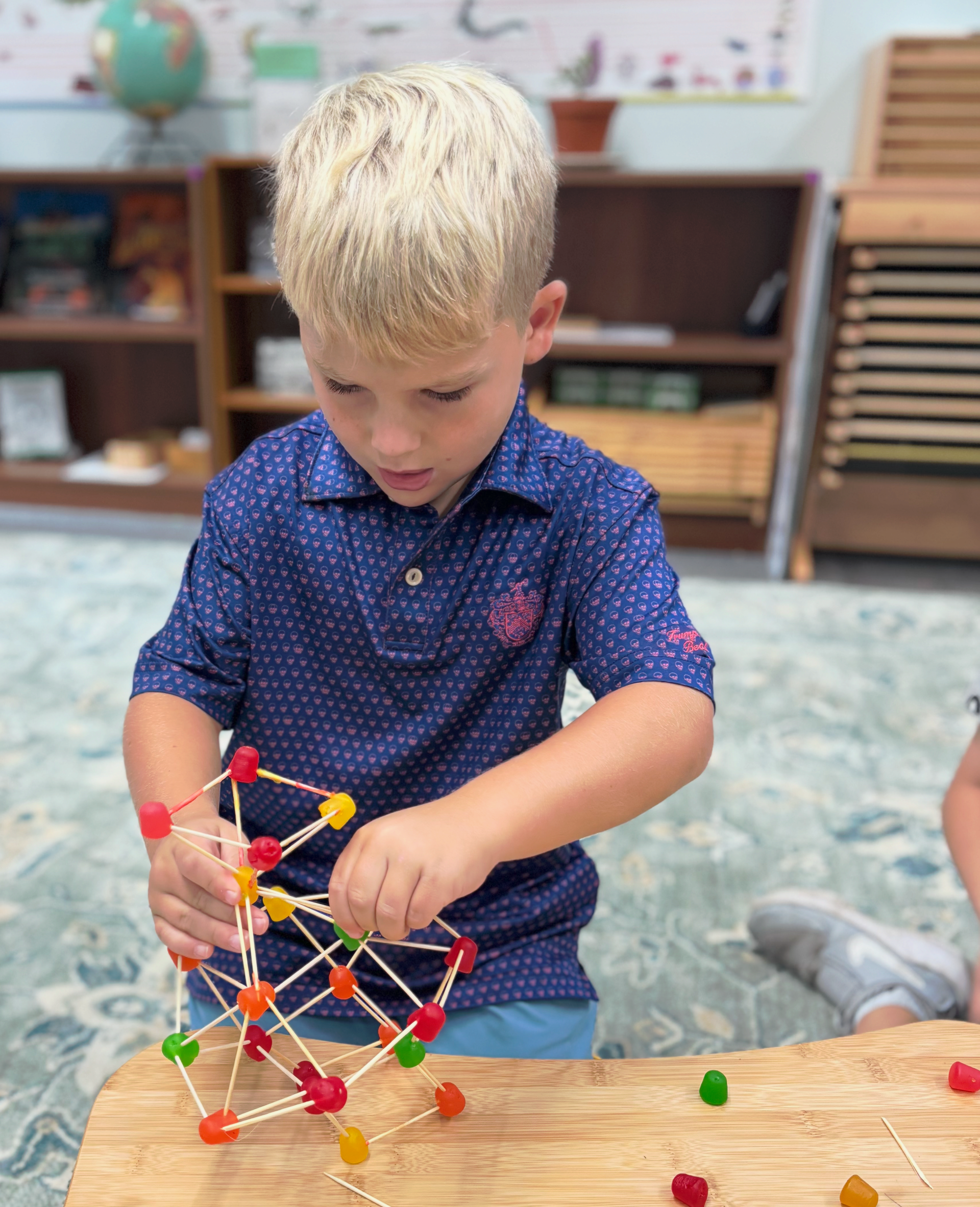 Child building a colorful magnetic structure on a classroom table