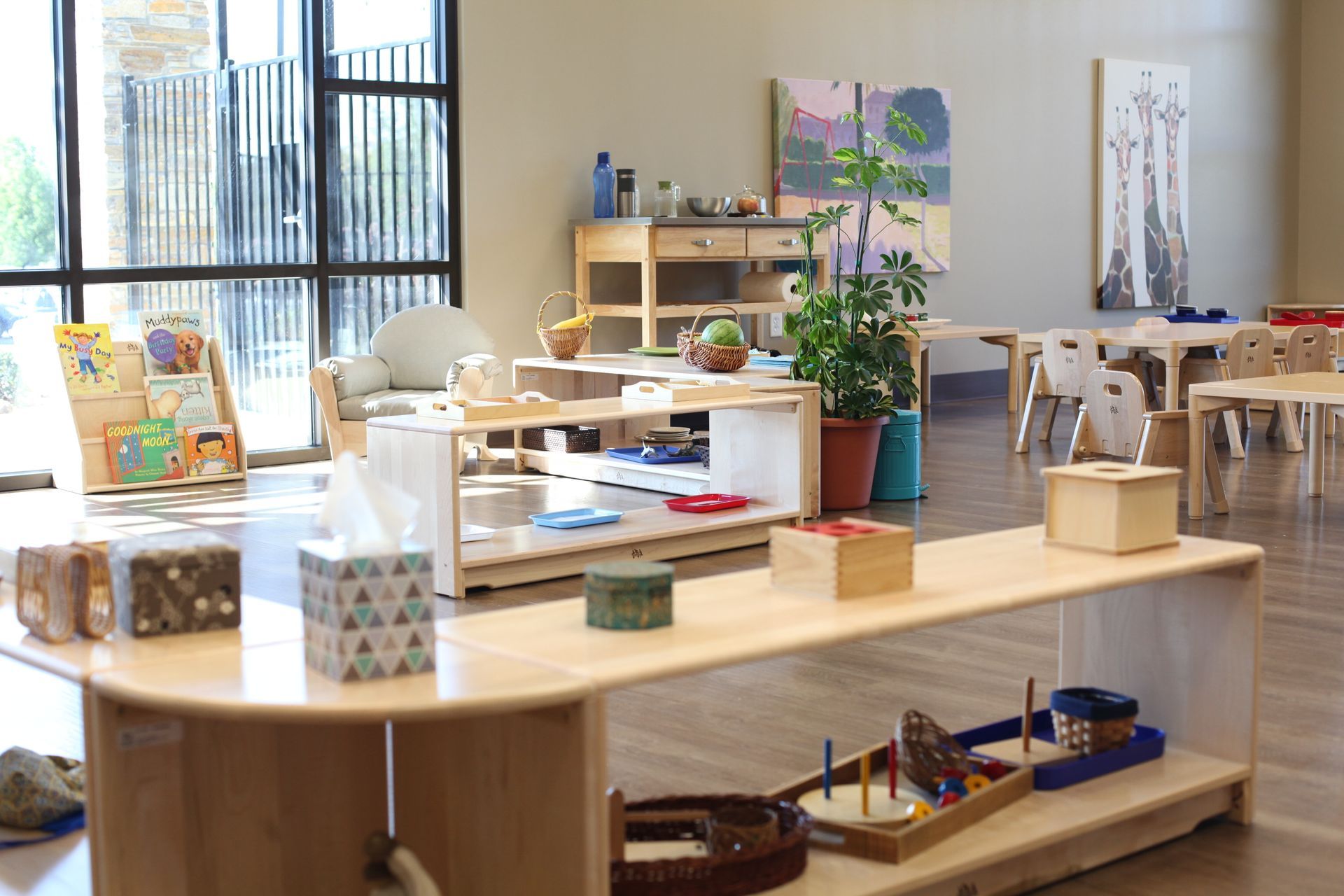 Bright classroom with wooden shelves, craft supplies, and paintings on display