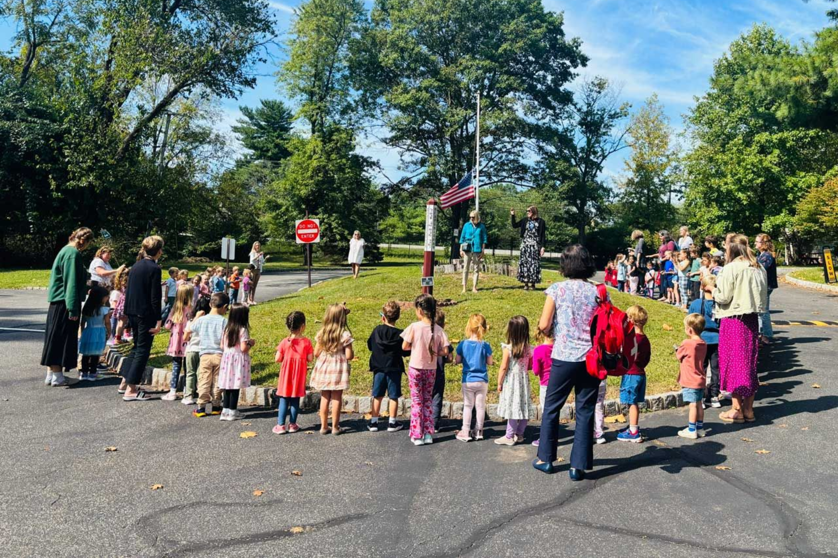 Montessori children and teachers gathered around a flagpole outside