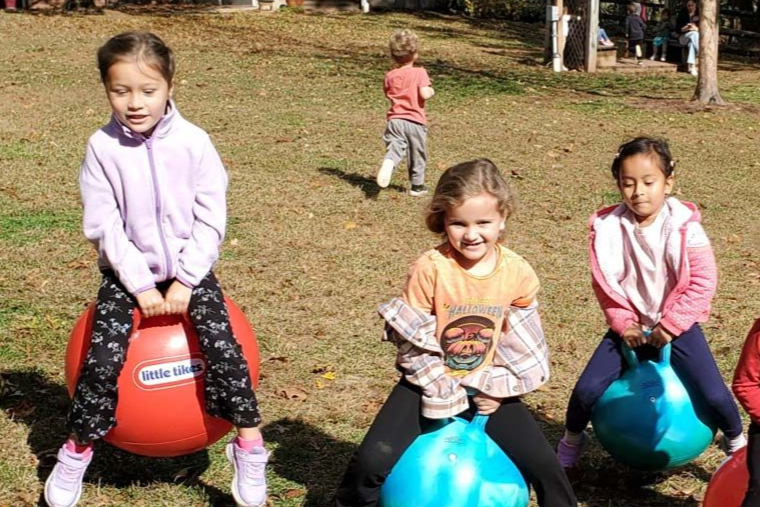 Montessori primary children bouncing on large hoppy balls outside