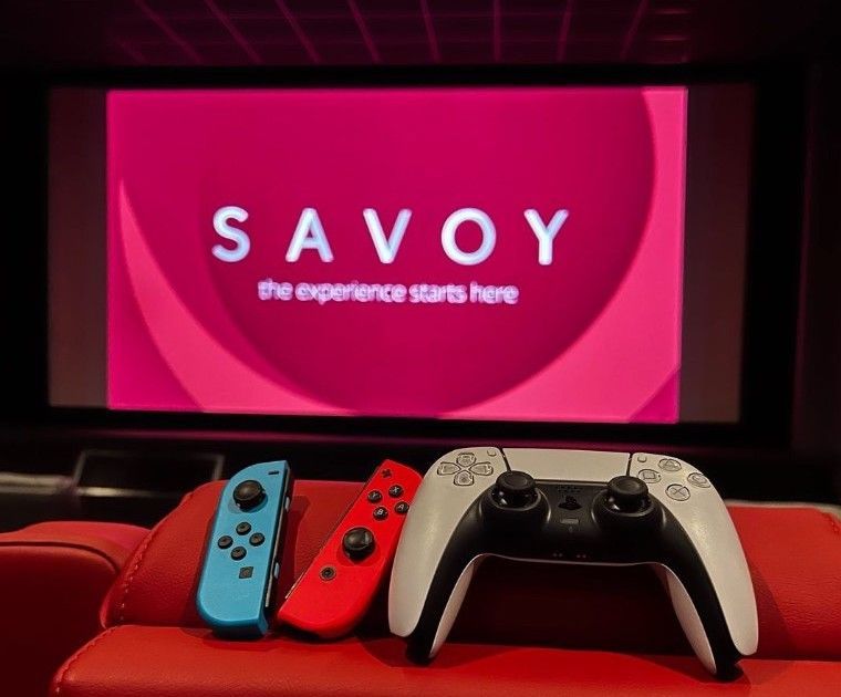 Joypad at Savoy cinemas - cinema gaming hire - Savoy logo on cinema screen in background with PS5 and switch controllers in foreground
