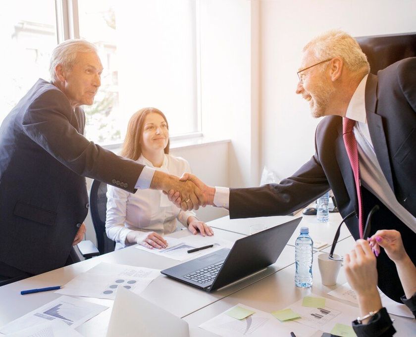 A group of business people are shaking hands in a conference room.