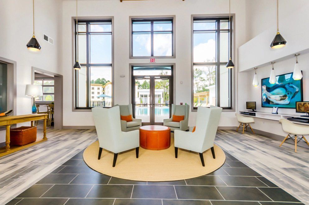 A clubhouse with chairs, a table, and a large window at Toledo Club Apartment, which offers apartments in North Port, FL.