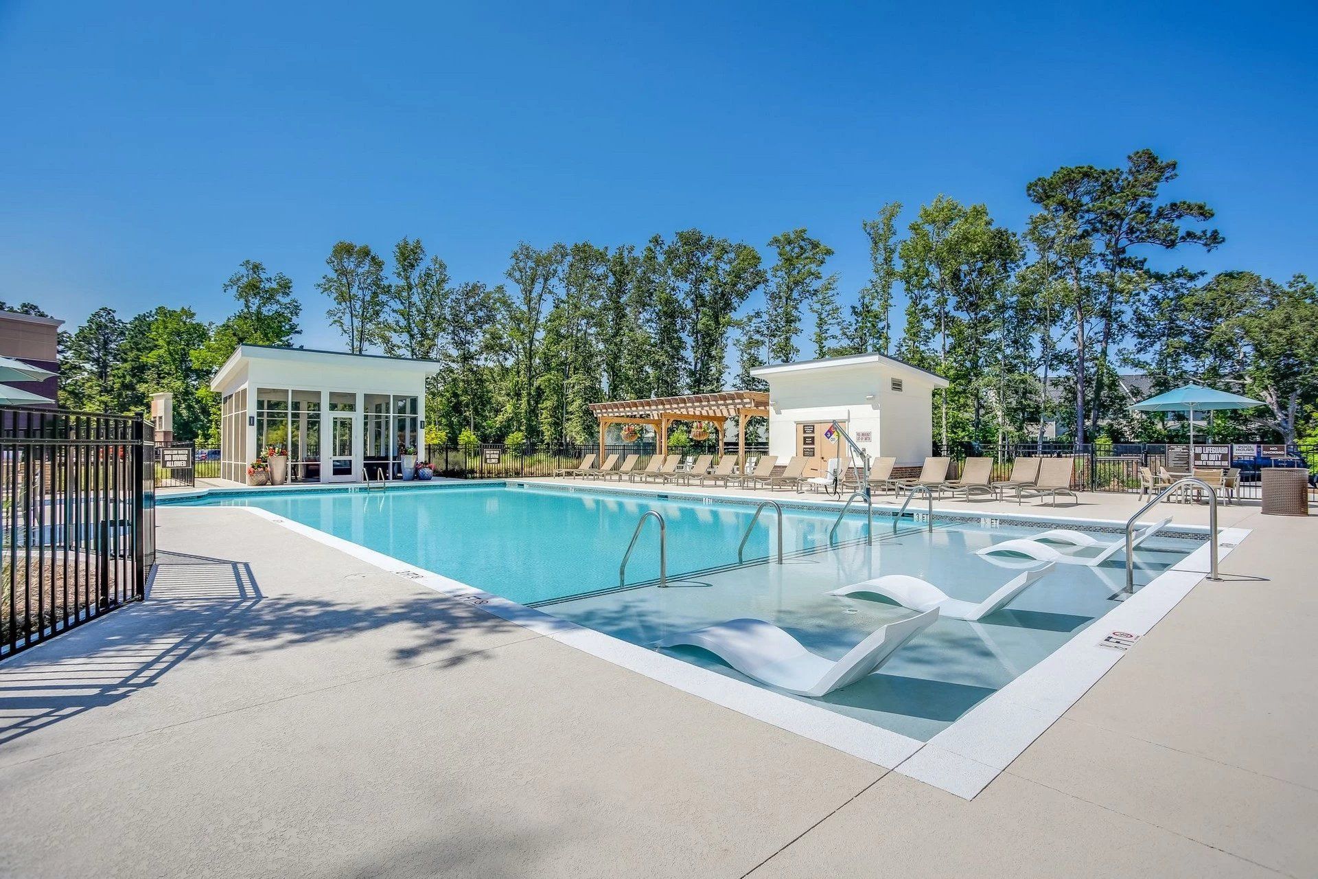 A large swimming pool surrounded by chairs and a fence at Toledo Club Apartment, which offers apartments in North Port, FL.