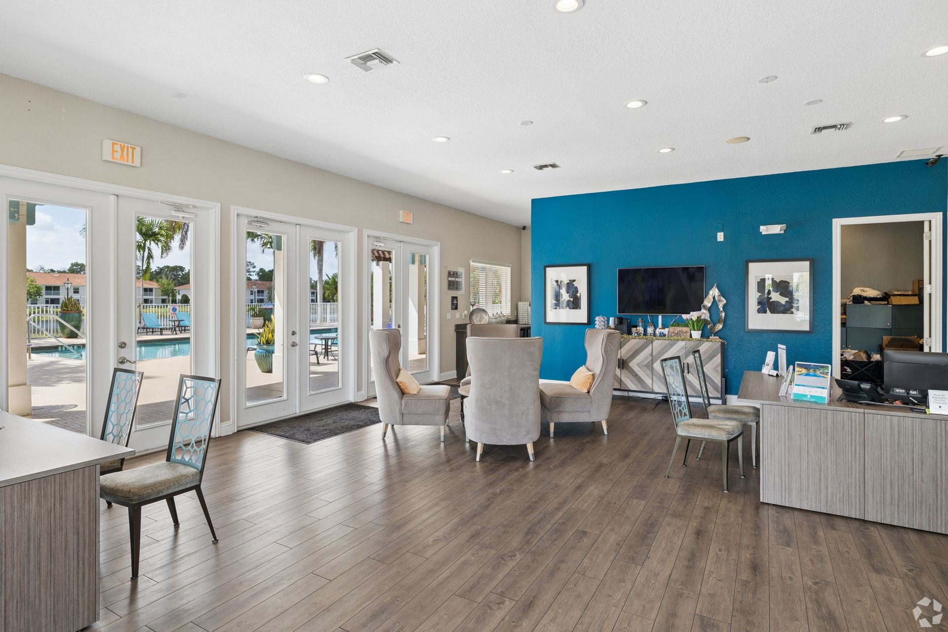 Bright modern waiting room with blue accent wall, chairs, desks, and large windows overlooking outside.