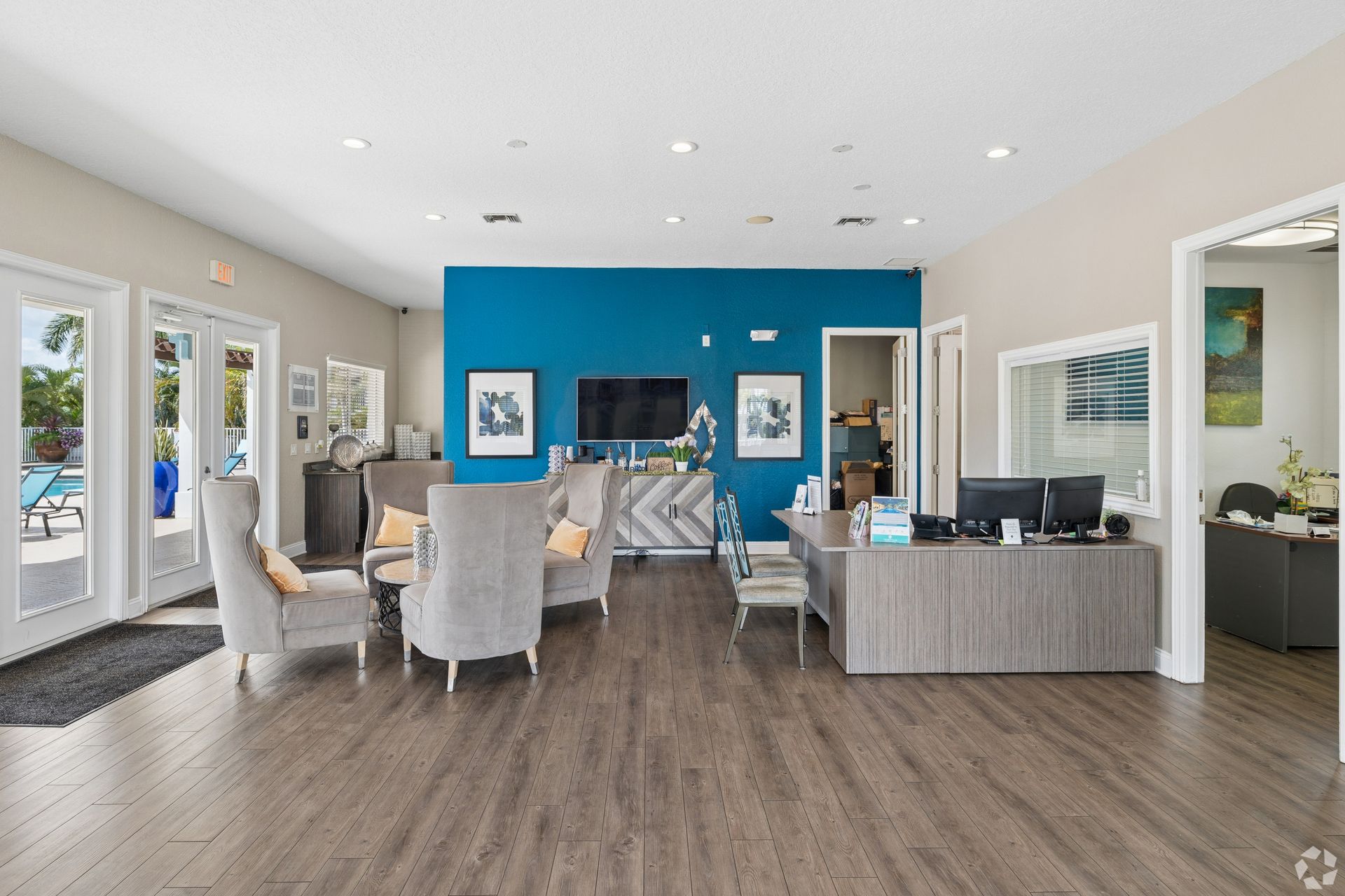 Open-concept dining and living room with blue accent wall, light furniture, and wood flooring.