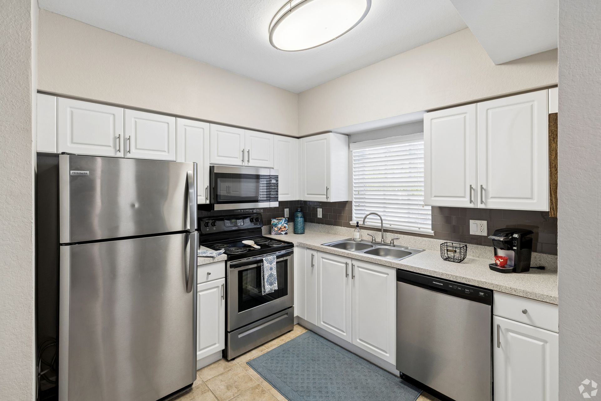 Small kitchen with stainless steel appliances, white cabinets, and a window over the sink.