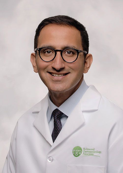 Portrait of a smiling doctor in a white coat and tie against a light gray background