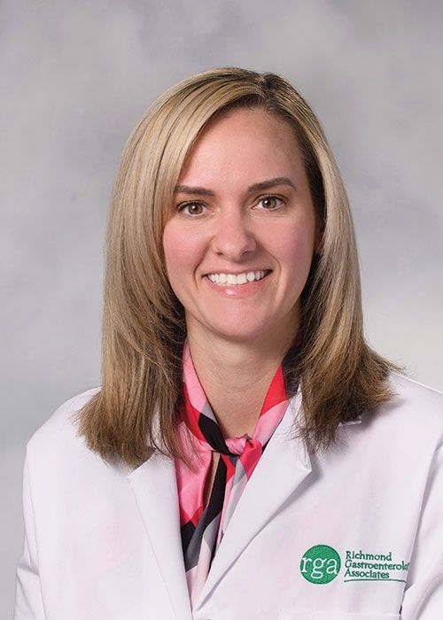 Portrait of a smiling doctor in a white coat and tie against a light gray background