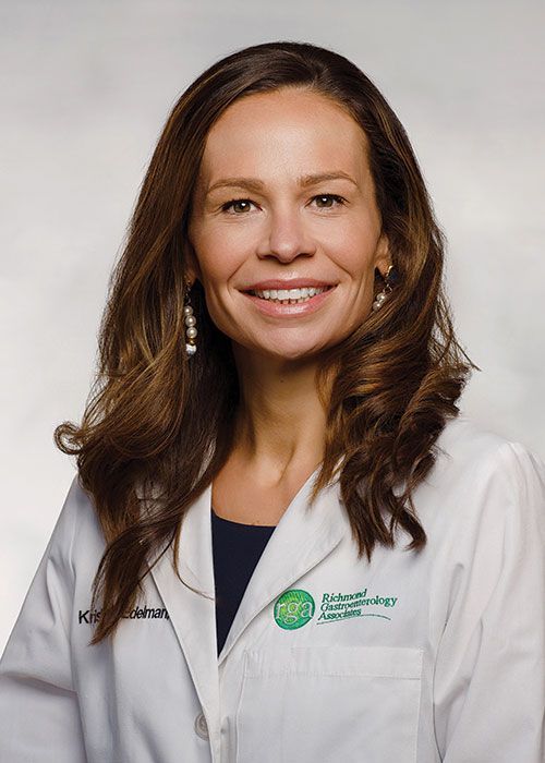 Portrait of a smiling doctor in a white coat and tie against a light gray background