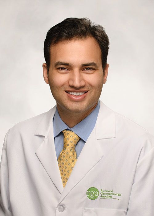Portrait of a smiling doctor in a white coat and tie against a light gray background