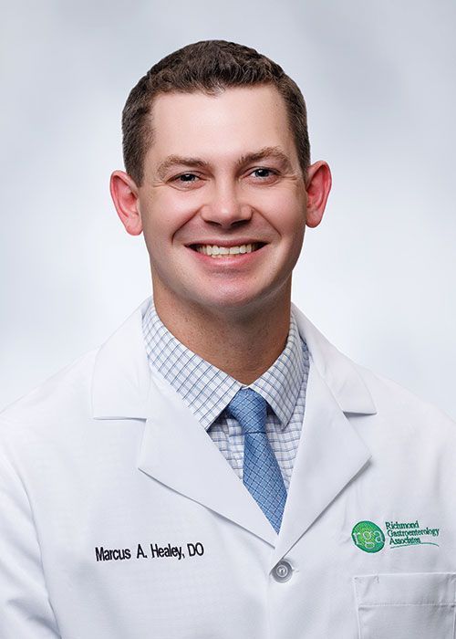 Portrait of a smiling doctor in a white coat and tie against a light gray background