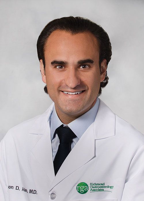 Portrait of a smiling doctor in a white coat and tie against a light gray background