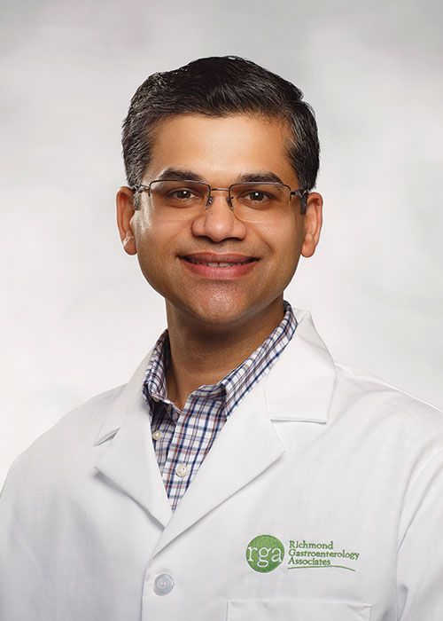 Portrait of a smiling doctor in a white coat and tie against a light gray background