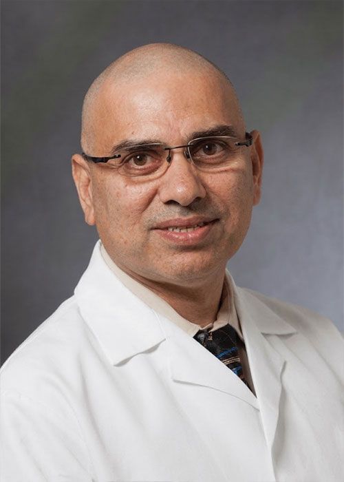 Portrait of a smiling doctor in a white coat and tie against a light gray background