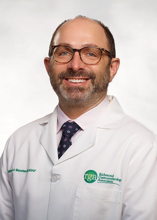 Portrait of a smiling doctor in a white coat and tie against a light gray background