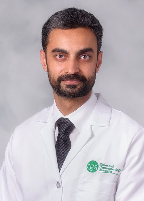 Portrait of a smiling doctor in a white coat and tie against a light gray background
