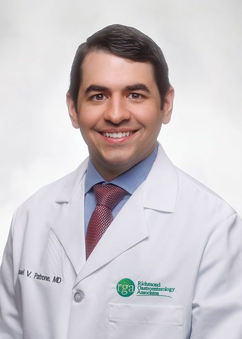 Portrait of a smiling doctor in a white coat and tie against a light gray background