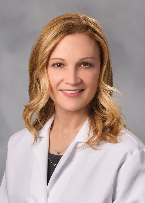 Portrait of a smiling doctor in a white coat and tie against a light gray background