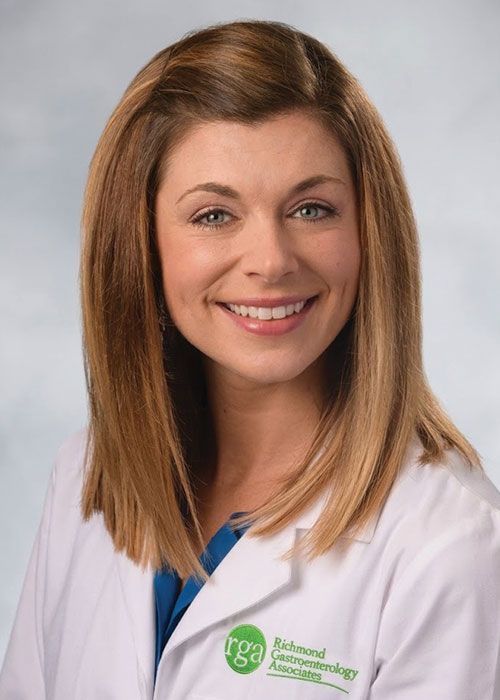 Portrait of a smiling doctor in a white coat and tie against a light gray background