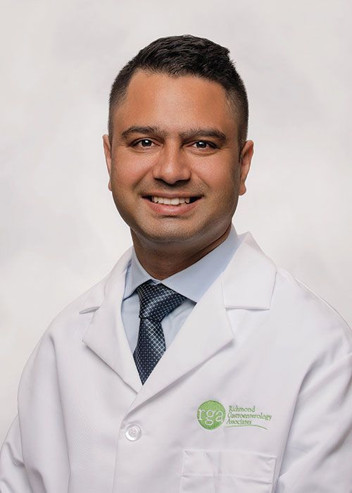 Portrait of a smiling doctor in a white coat and tie against a light gray background