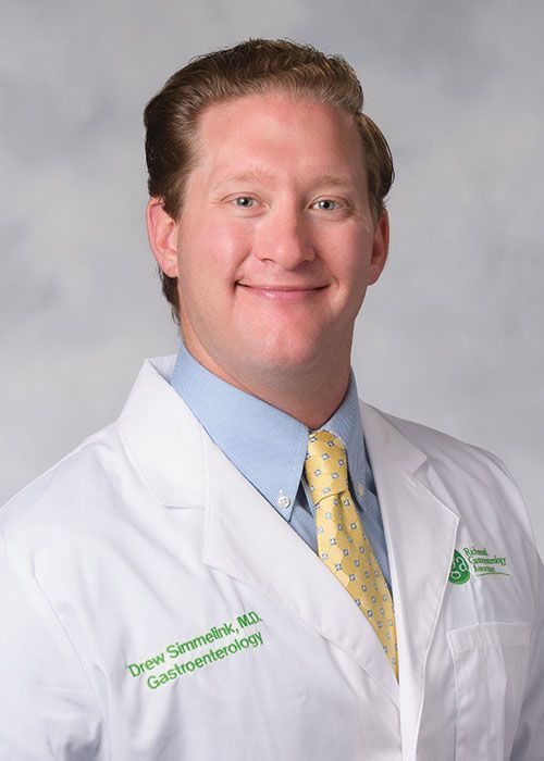 Portrait of a smiling doctor in a white coat and tie against a light gray background