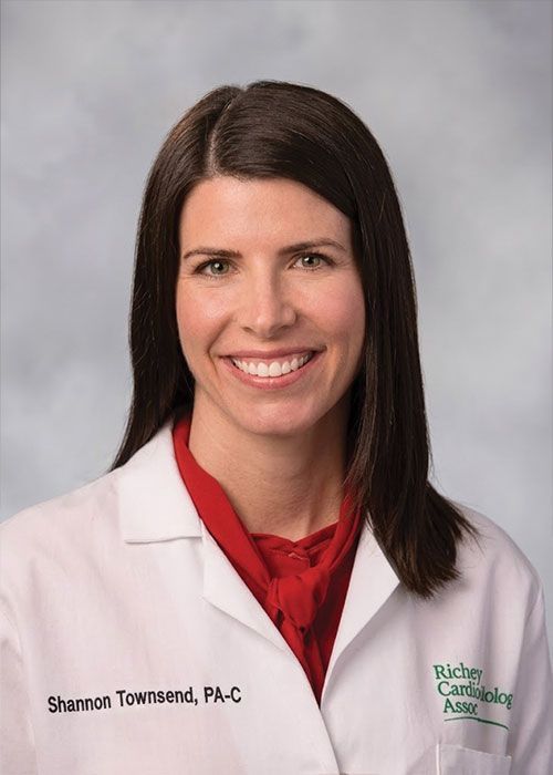 Portrait of a smiling doctor in a white coat and tie against a light gray background