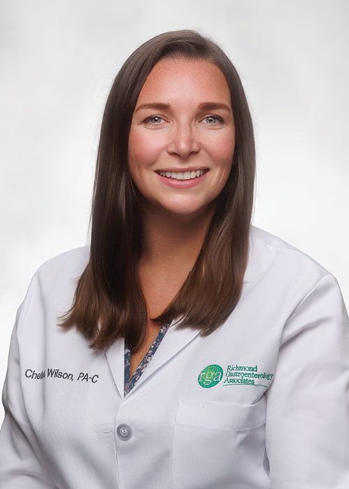 Portrait of a smiling doctor in a white coat and tie against a light gray background