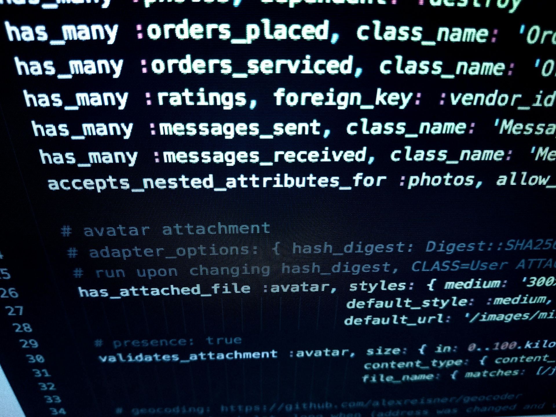 Code on a screen, showing database relationships with Ruby on Rails syntax.