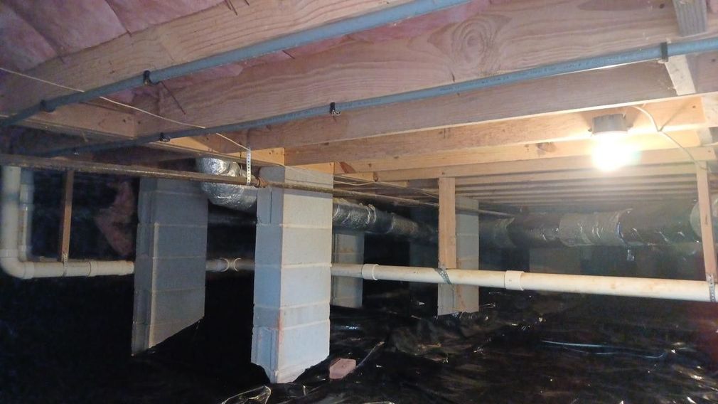 Wooden ceiling under construction with plumbing and wiring visible.