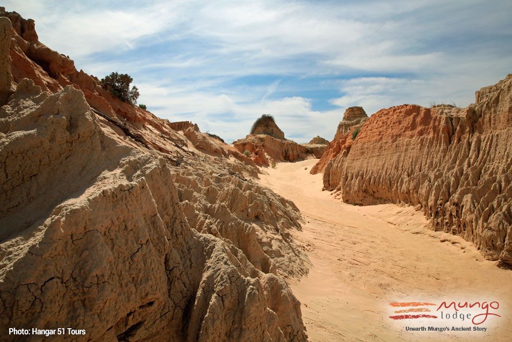 Sandy desert canyon with rugged orange cliffs under a blue sky