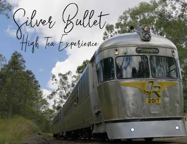 Silver Bullet heritage train in silver and yellow on a forest track, titled “High Tea Experience”