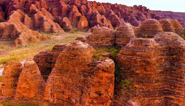 Orange rocky canyon landscape with layered cliffs and rugged hills under warm light