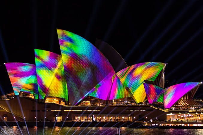 Sydney Opera House lit with colorful rainbow projections at night