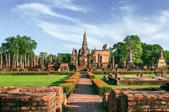 Ancient temple ruins with stone towers and manicured gardens under a clear blue sky
