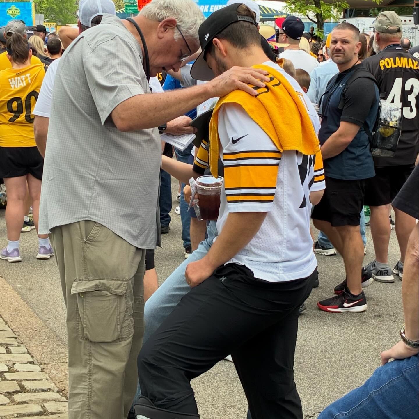 An SFOI evangelist praying with a young fan at the NFL Draft — the conversations that matter most often start where a hard one ended.