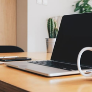 A laptop is open on a desk next to a cup