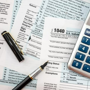 A pen and calculator are on top of a 1040 tax form
