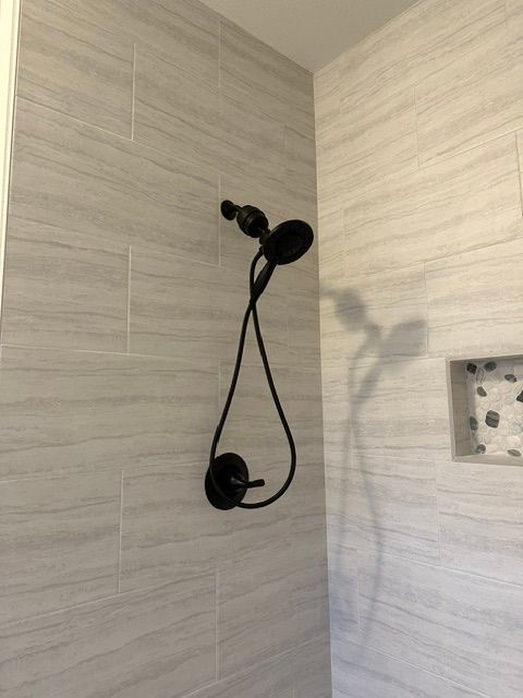 Black showerhead and handheld shower on beige tiled bathroom wall.